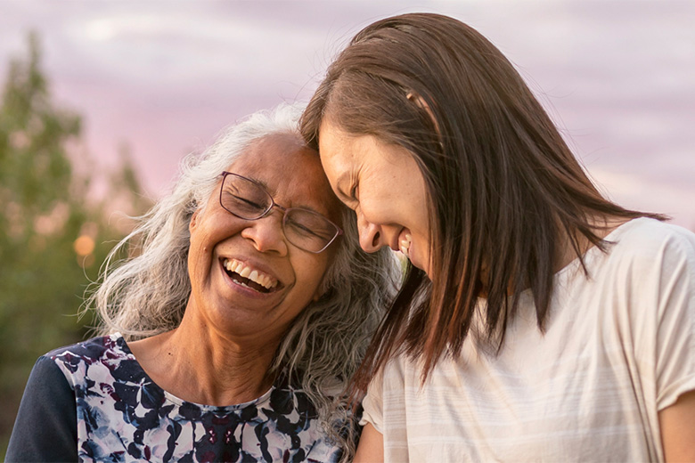 Mother and daughter laugh outside